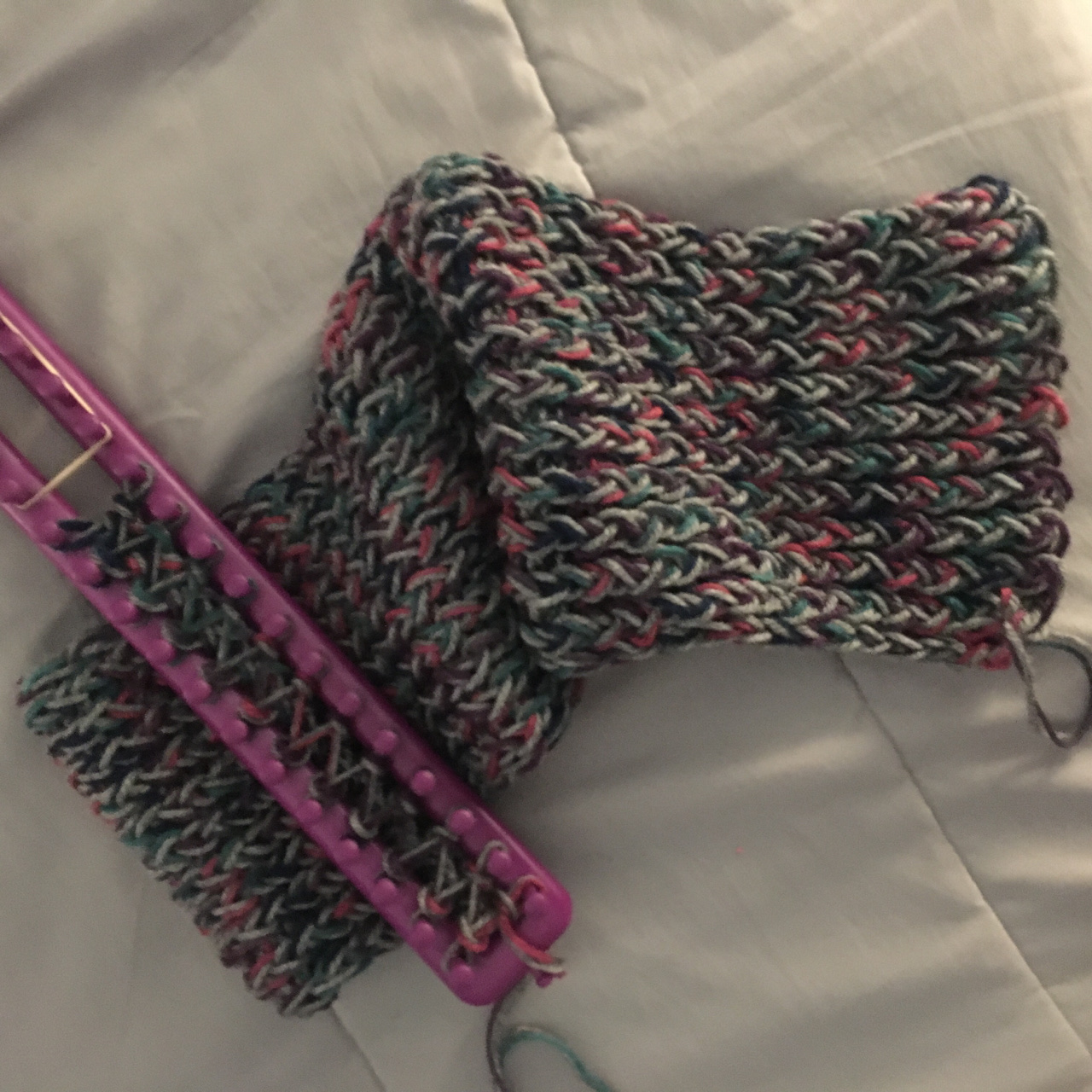 The thick, squishy purple, green, and grey grow longer out of the 36-peg purple rake loom, laid out on a grey background.