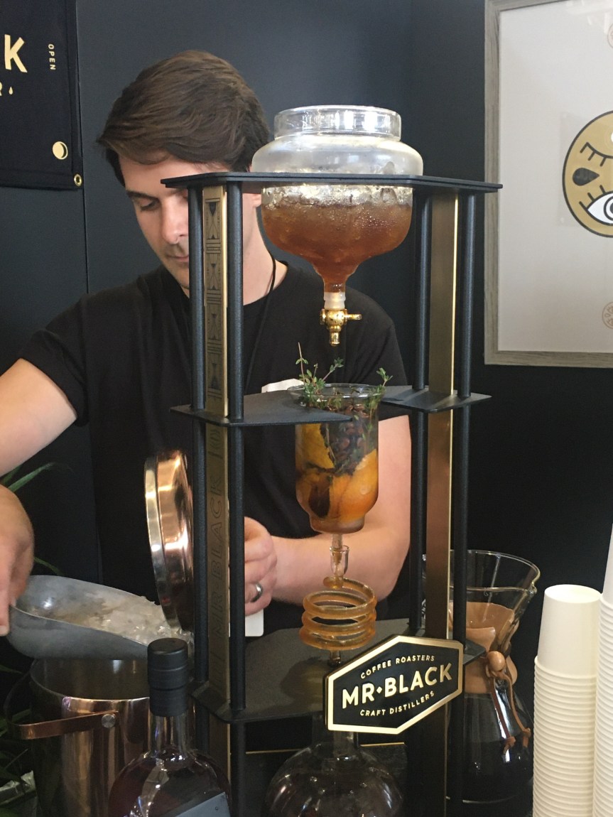 A representative from Mr. Black siphons off herbal infused boozy concoction for mixture into coffee liqueur.