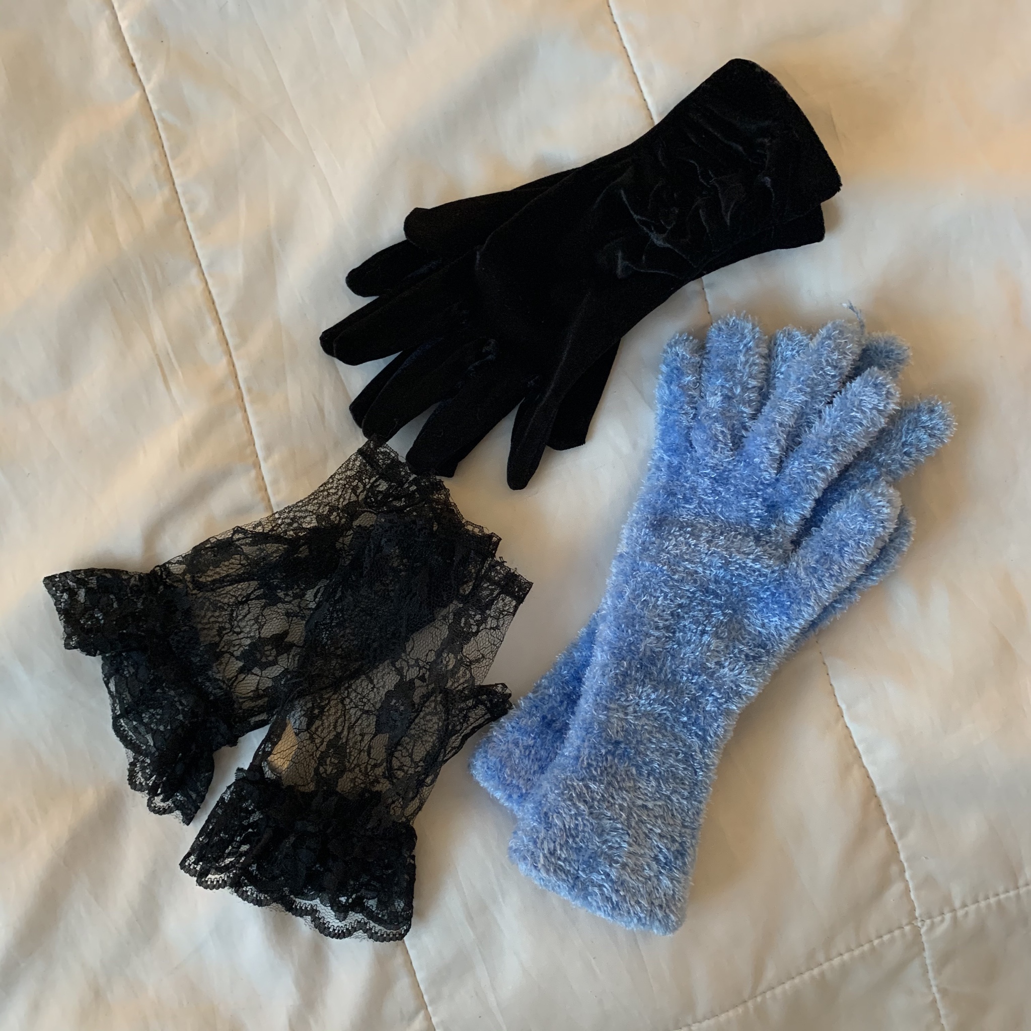 Another three pairs of gloves laid out, fuzzy, pale blue, velvety black, and lacy black.