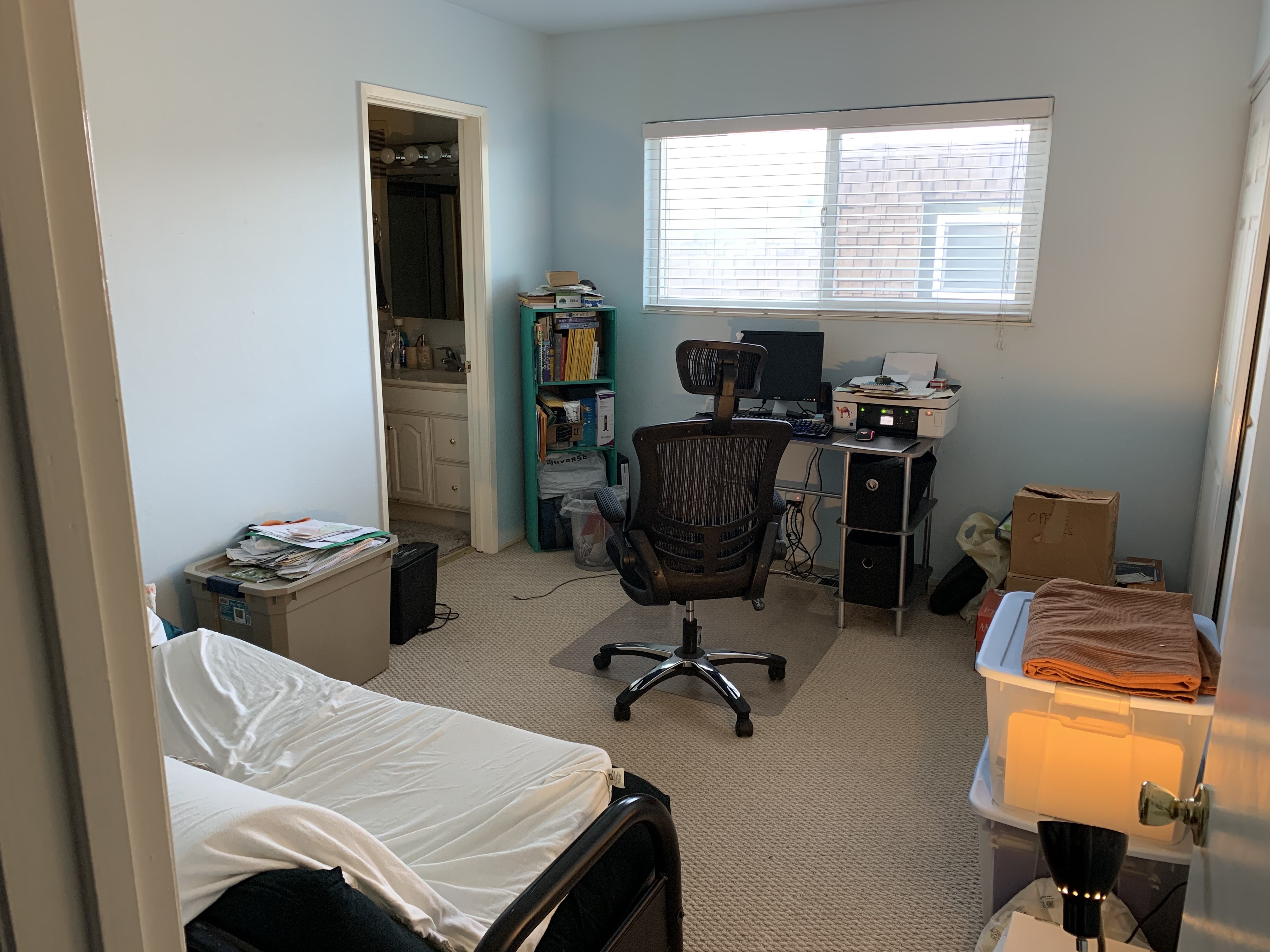 View of our office from the doorway, before our trip to Ikea. A small desk and office chair face the opposite wall under a window and there’s a futon just inside the door to the left.