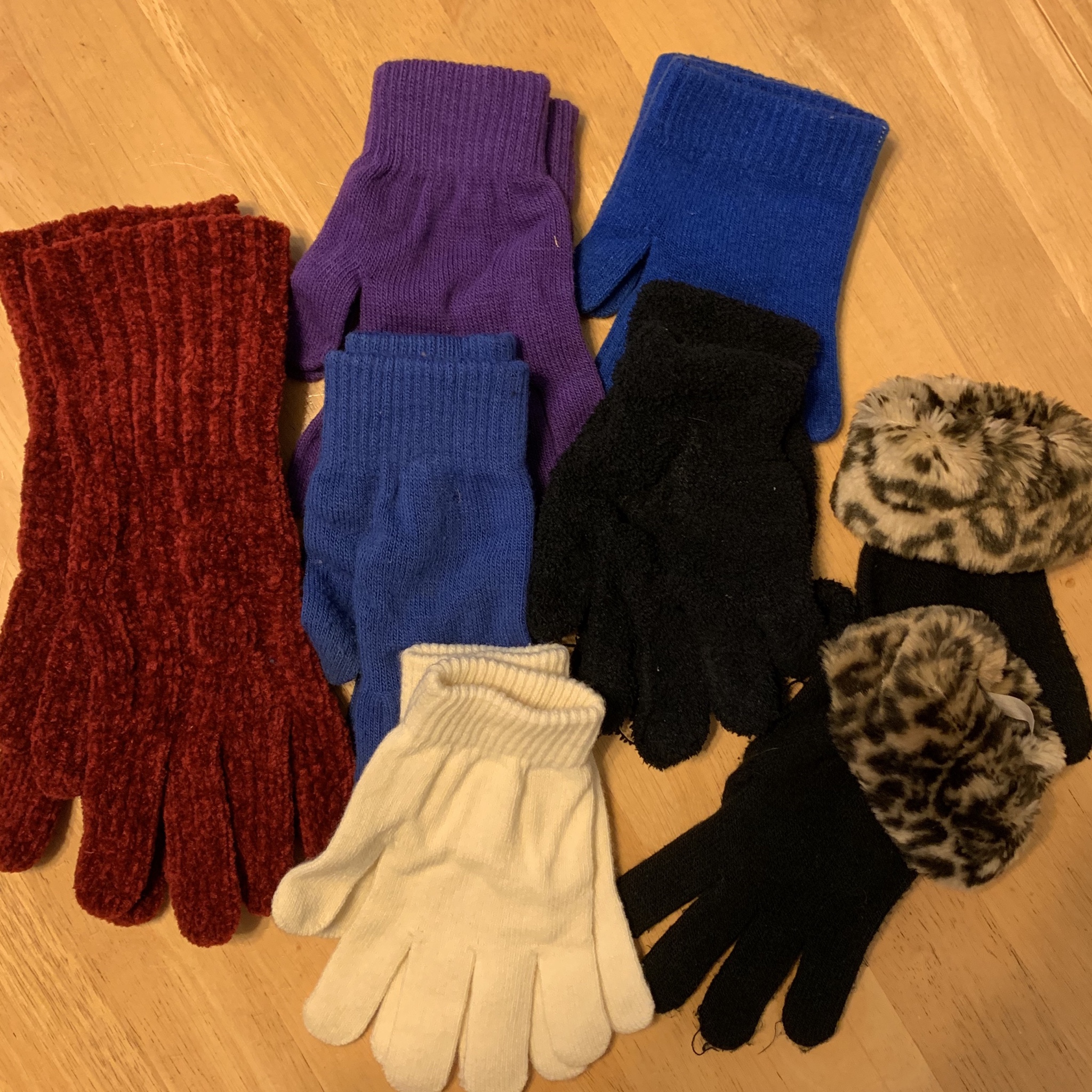 A collection of fashionable winter gloves, in burgundy knit, black with leopard print cuffs, and purple, blue, and white cotton.