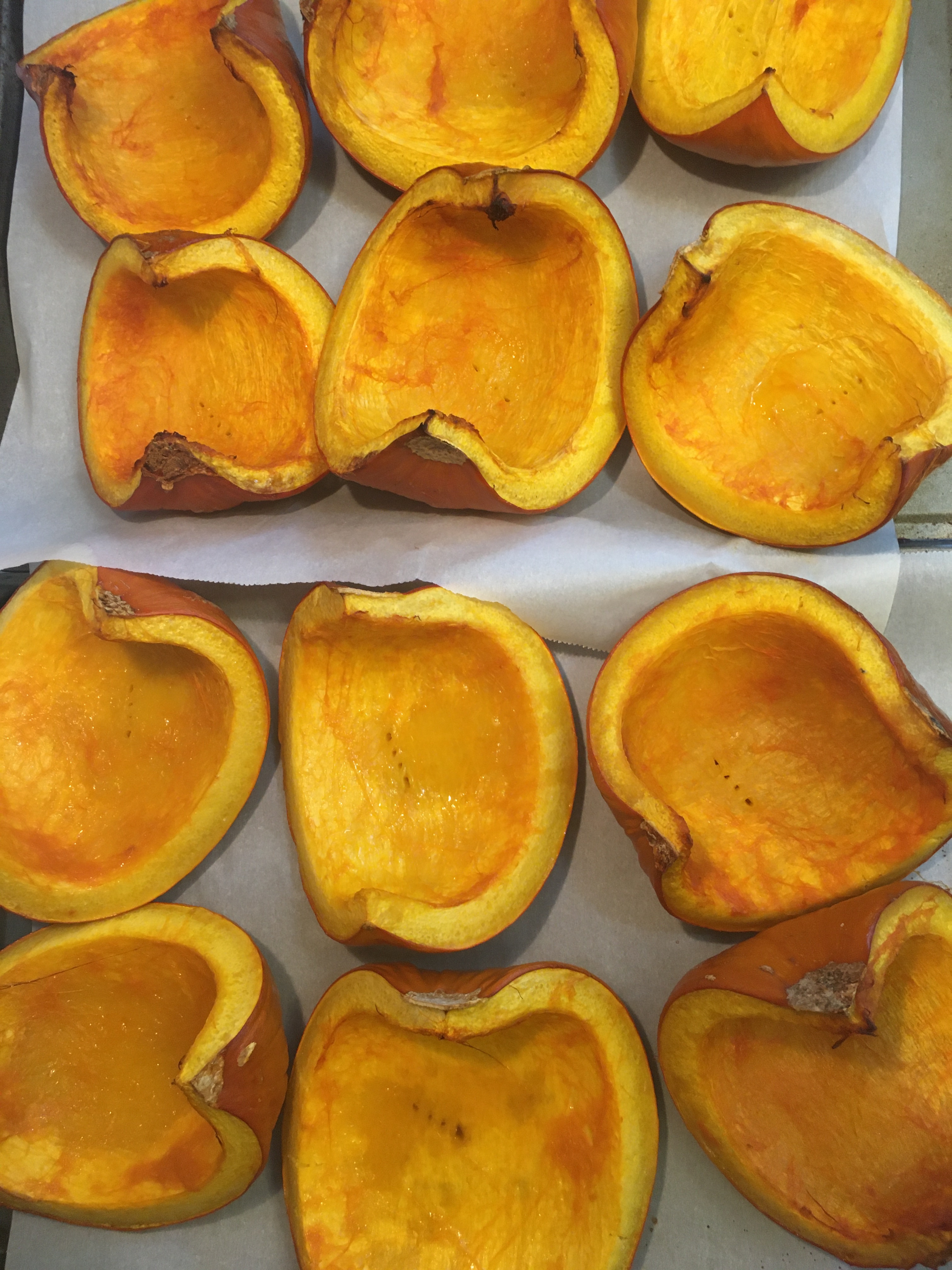 Sugar pumpkin quarters, scraped clean of guts and seeds and lightly oiled, lay roasted on baking sheets.